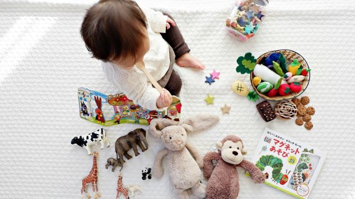 Image taken from above of young girl on rug surrounded by toys