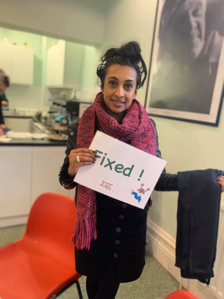Photo of someone at a repair cafe holding up a fixed sign